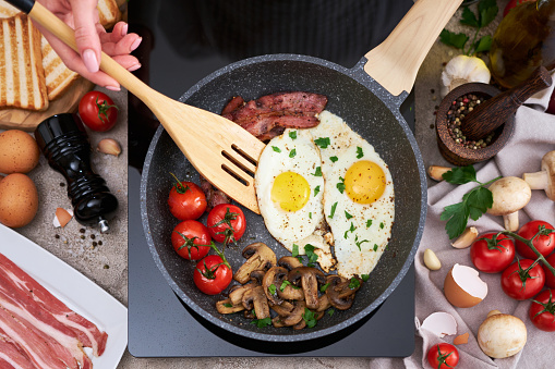 Frying eggs and bacon on a pan on induction hob at domestic kitchen.