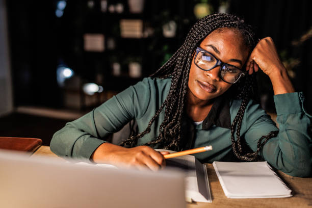 istock Tired female student taking notes and studying at her desk late at night 1446120415