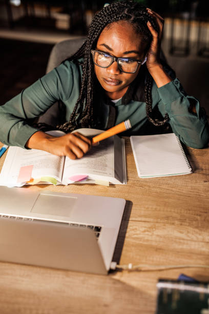 istock Tired female student taking notes and studying at her desk late at night 1446120417