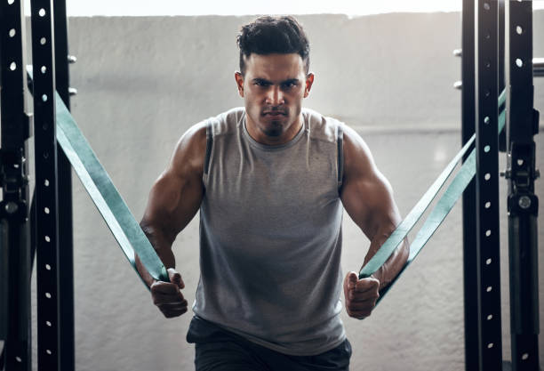 hombre, banda de resistencia y culturismo en el entrenamiento de gimnasio, entrenamiento y ejercicio con salud, bienestar y fuerte motivación muscular. retrato, entrenador personal o culturista en fitness con mentalidad de poder - brain gym fotografías e imágenes de stock