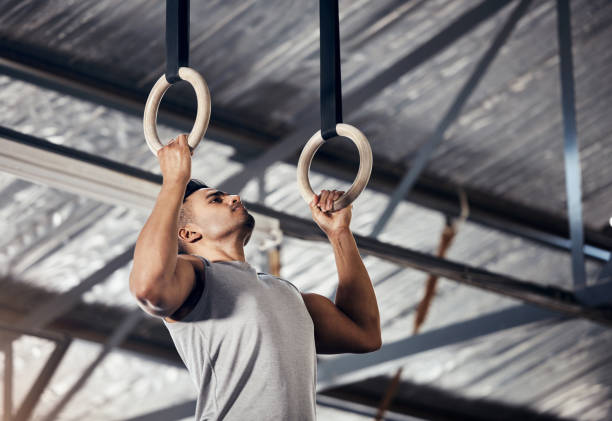 istock Fitness, exercise man in gymnastics gym during pull up, training or exercise on rings. Young sports athlete or gymnast, strong mindset and start workout to improve muscle or cardio at sport club 1446121879
