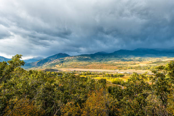 vista de grande angular de aspen, colorado montanhas rochosas no pôr do sol tempestuoso da tempestade com nuvens nubladas céu de paisagem azul por carvalhos em primeiro plano - 24239 - fotografias e filmes do acervo