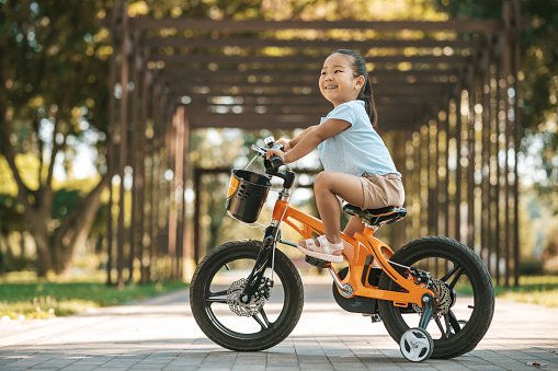 Riding a bike. Happy little girl riding a bike and looking excited