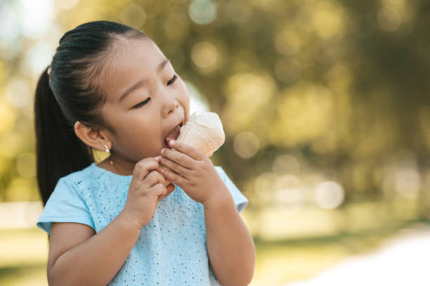 Cute little girl eating ice-cream and looking contented Tasty ice-cream. Cute little girl eating ice-cream and looking contented asian little chinese girls eating ice cream stock pictures, royalty-free photos & images