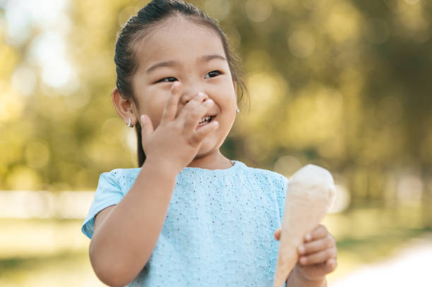 Cute little girl eating ice-cream and looking contented Tasty ice-cream. Cute little girl eating ice-cream and looking contented asian little chinese girls eating ice cream stock pictures, royalty-free photos & images
