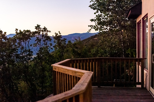 Aspen, Colorado house real estate home with wooden deck railing on balcony terrace and autumn foliage in roaring fork valley and view of sunset in evening