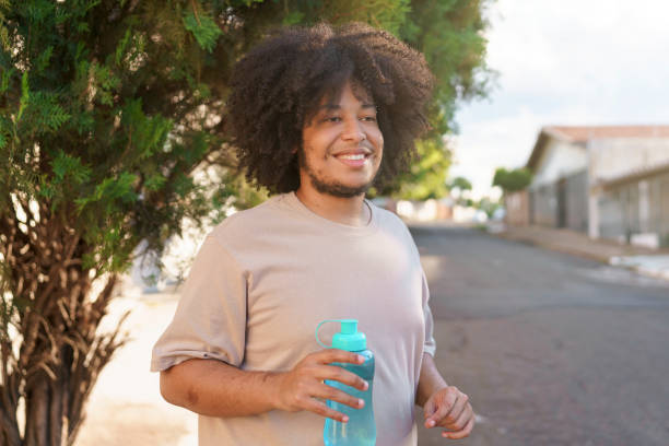 istock Young man with afro hair outdoors holding water bottle 1446154393