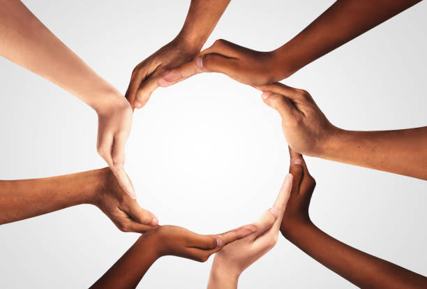 Conceptual symbol of multiracial human hands making a circle on white background with a copy space in the middle. The concept of unity, cooperation, partnership, teamwork and charity.