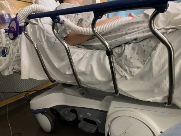 Side of a hospital bed with a patient laying in bed (no face visible) stock photo