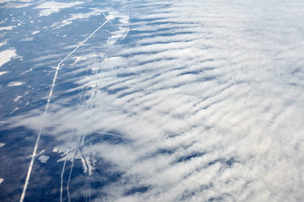 Commercial airplane flying over bright blue sky and white clouds.
