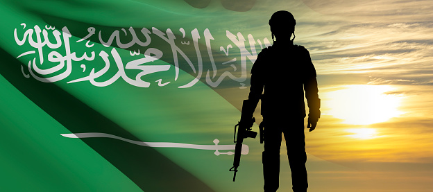 Silhouette of soldier on background fo susnet and Saudi Arabia flag. Concept for National Holidays