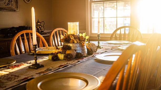 An empty Thanksgiving Dinner table with wooden chairs with sunset light from window
