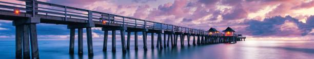 panorámica del muelle de naples al atardecer con un cielo púrpura en florida, ee. uu. - florida naples florida pier beach fotografías e imágenes de stock