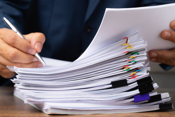 istock Business man hand writing on Stack overload document report paper with colorful paperclip, business and paperless concept. 1446173607