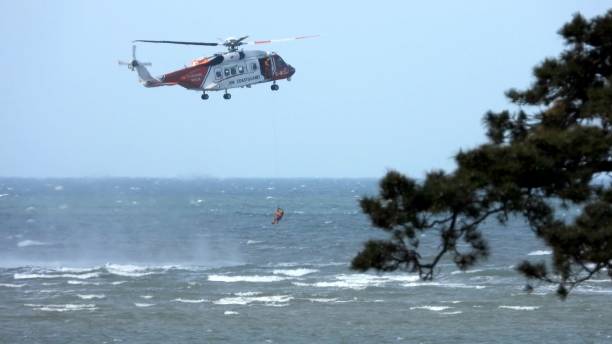 załoga helikoptera straży przybrzeżnej przeprowadza szkolenie ratownicze w traeth coch, anglesey - coch zdjęcia i obrazy z banku zdjęć
