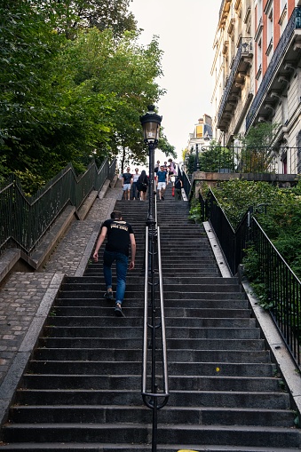Paris, France – August 15, 2022: A vertical shot of the stairs in Montmartre, Paris, France with people walking around