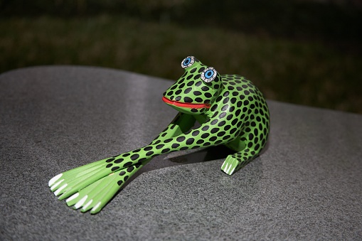 A closeup shot of a green frog toy on stone