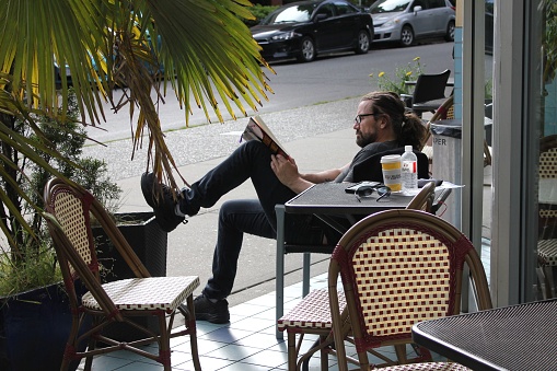 Vancouver, Canada – May 28, 2022: A man reading a book at coffee shop in downtown Vancouver, British Columbia, Canada
