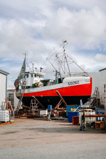 toma vertical de un barco de pesca rojo de estilo escandinavo en tierra que debe ser reparado - unready fotografías e imágenes de stock