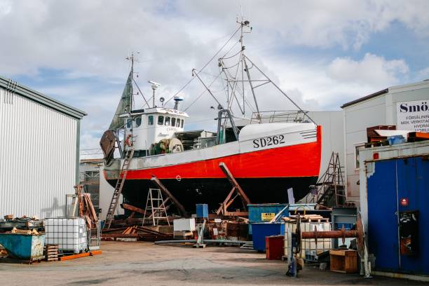 bateau de pêche rouge de style scandinave à terre devant faire l’objet de réparations - unready photos et images de collection