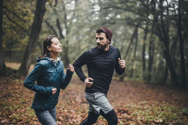 istock Young athletic couple running during cold day in misty forest. 1446184929