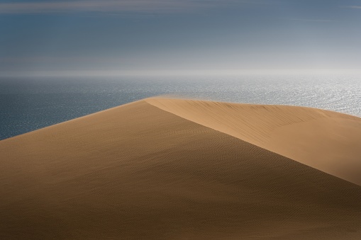 A beautiful view of a soft sands hill with sea in the background