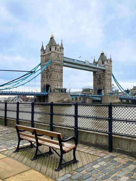 istock Vertical low-angle of Tower Bridge from a platform with a bench cloudy sky background 1446187338