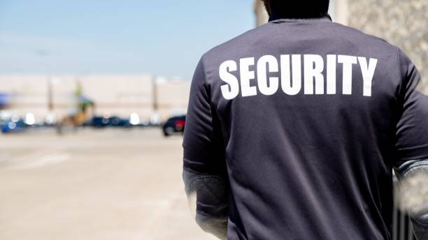 istock Security person standing outdoors in the sun, shot from back 1446189053