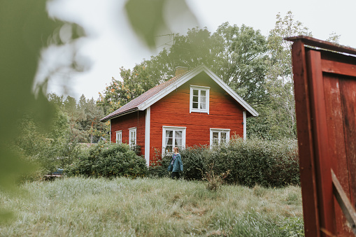 Photo series of young nordic woman spending time in her traditional summer cottage.