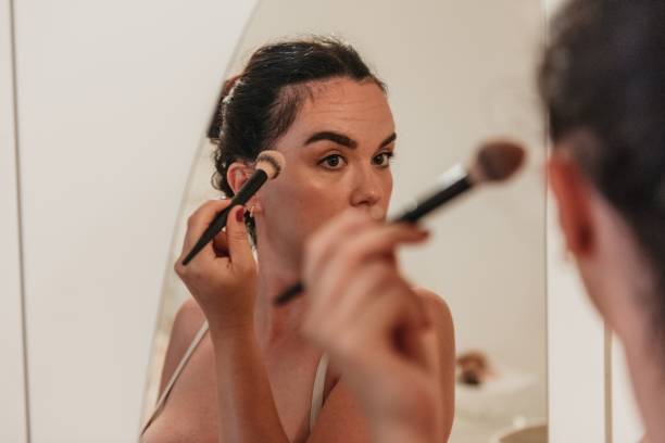istock Caucasian woman looking at mirror and applying makeup 1446196535