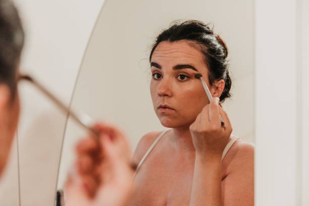 istock Caucasian woman looking at mirror and applying makeup 1446196551