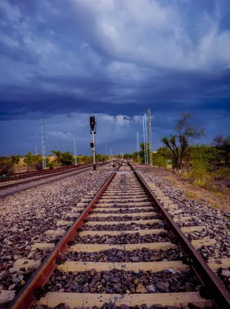 A vertical shot of an empty railway with pebbles in its internodes under the gloomy sky