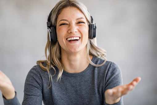 Happy businesswoman talking during conference call in the office and looking at camera. Copy space.