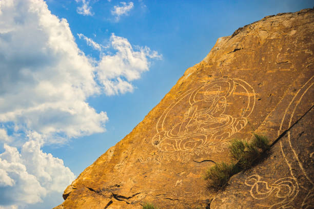 istock An ancient Buddha image on a stone rock against a sky with clouds 1446201081