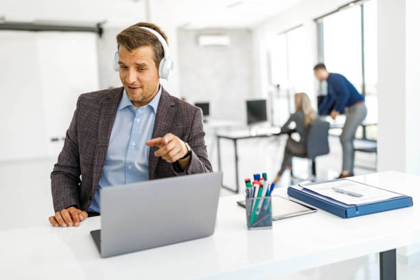 istock Smiling businessman having a web conference over laptop in the office. 1446201180