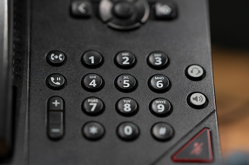 Black Polycom office phone with focus on dialling numbers