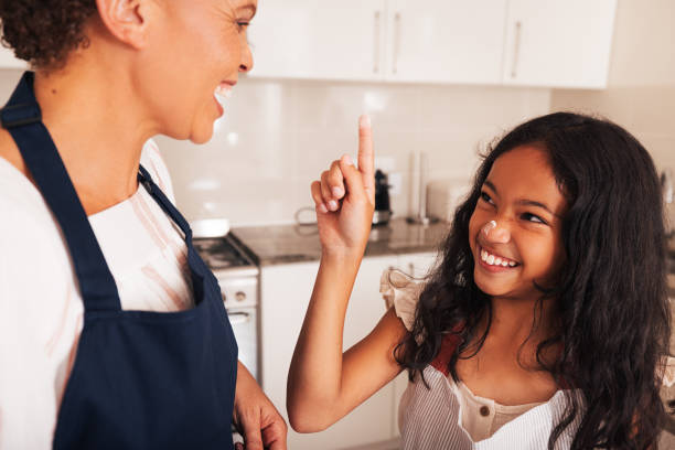 istock Smiling girl trying to make marks on granny's face using flour 1446205773