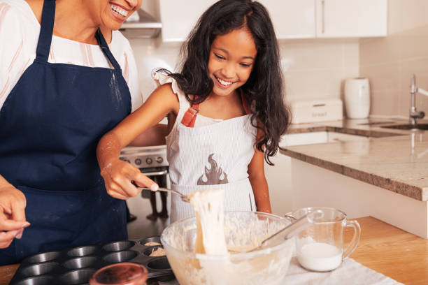 istock Smiling girl scoops batter from a bowl 1446205826