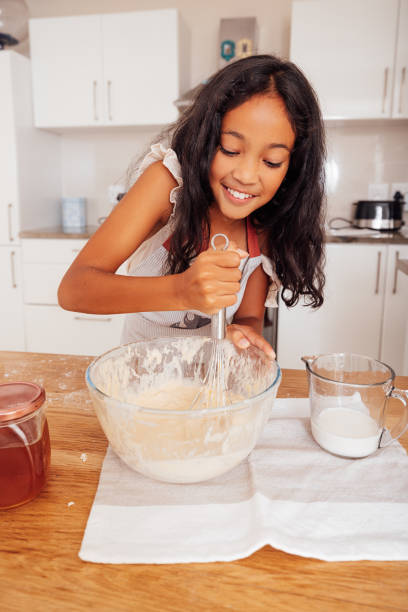 istock Smiling girl mixing a dough. Cheerful kid making dough for cupcakes in the kitchen. 1446207498