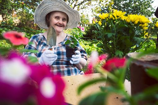 Happy woman with Down Syndrome ready to planting flowers. Gardening.