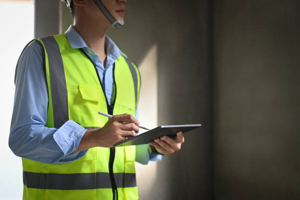 istock Cropped shot of engineer man wearing safety helmets and vests using diigtal tablet, checking project details at construction site. 1446207963