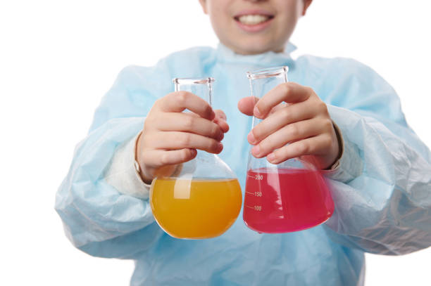 Selective focus on laboratory glass flasks with chemical liquid substances, in the hands of a schoolboy at chemistry class, conducting science experiments, isolated on white background. Copy ad space