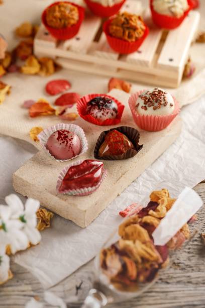 istock Vertical shot of different little handmade chocolates on a white  background, surrounded with petals 1446210867