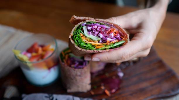 istock Appetizing vegetarian rolls wrapped in flatbread filled with various vegetables. On a wooden plate, a healthy breakfast of a vegetable dish and a drink with fruits and berries. Delicious vegan. 1446215074