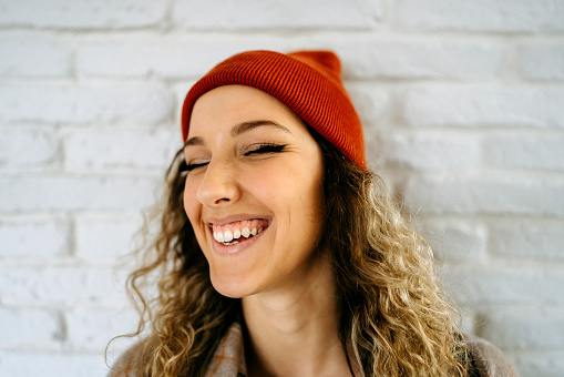 Portrait of cheerful laughing teenage girl in front of white wall