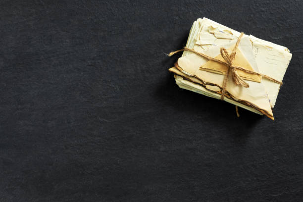 stack of old torn vintage letters on yellowed paper against black granite table. - writing manuscript ancient postcard imagens e fotografias de stock