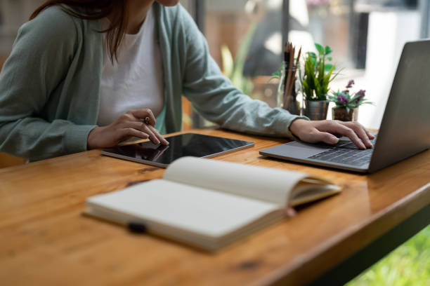 istock Asian woman writing making list taking notes in notepad and digital tablet working or learning on laptop indoors- educational course or training, seminar, education online concept 1446221924