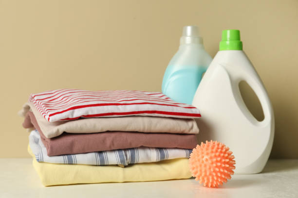 istock Orange dryer ball, laundry detergents and stacked clean clothes on white table 1446221974