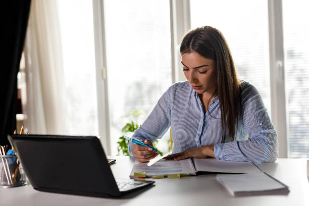 istock Young woman sitting at home office desk, highlighting important notes while studying 1446222175