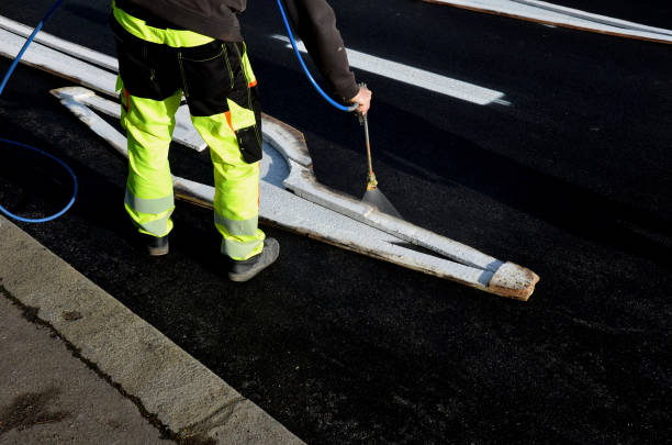 istock restoring horizontal markings at intersection with roundabout and crossing. they spray new symbols using a stencil. then they cover it with sand pigment does not stick wheel, reflective green clothing 1446222231